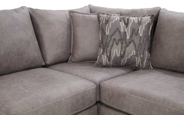 Section of a gray microfiber sectional sofa with plush cushions and a decorative gray patterned throw pillow, showcasing modern living room furniture.
