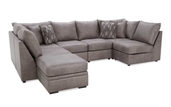 Gray fabric sectional sofa with chaise lounge, plush cushions, and patterned throw pillows, designed for modern living room comfort.