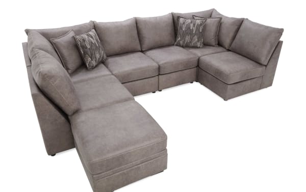 Large L-shaped sectional sofa upholstered in soft gray fabric with plush cushions and patterned accent pillows, ideal for modern living rooms.