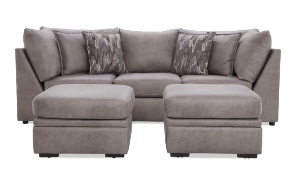 Modern gray fabric sectional sofa with two matching ottomans, plush cushions, and patterned throw pillows, ideal for living room seating.