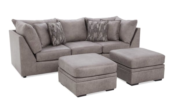 Modern gray fabric sectional sofa with two matching ottomans, plush cushions, and patterned throw pillows, ideal for living room seating.