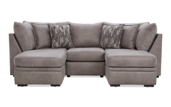 Gray sectional sofa with plush cushions, two patterned accent pillows, and a modern, soft fabric upholstery ideal for living room seating.