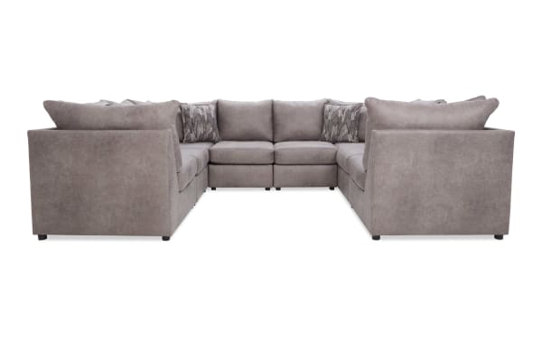 Large U-shaped sectional sofa in soft gray fabric with plush cushions and patterned throw pillows, ideal for spacious living rooms.