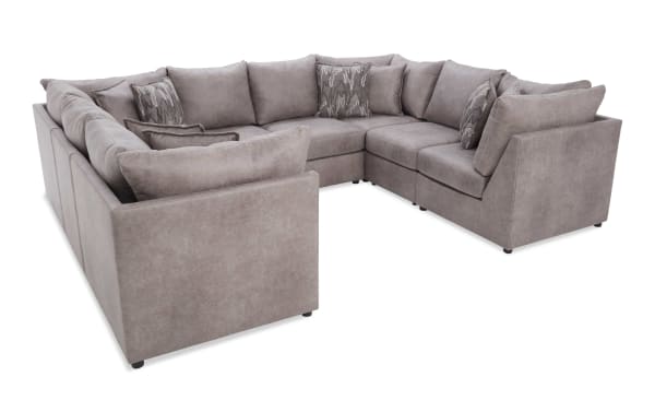 Large L-shaped sectional sofa upholstered in soft gray fabric, featuring plush cushions and patterned throw pillows, ideal for spacious living rooms.