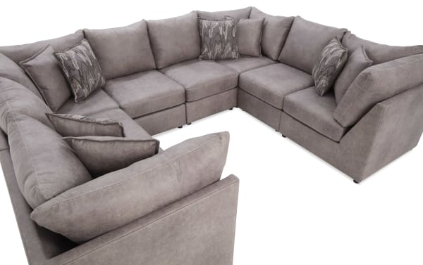 Large U-shaped sectional sofa in taupe microfiber fabric with plush cushions and patterned accent pillows, ideal for spacious living rooms.
