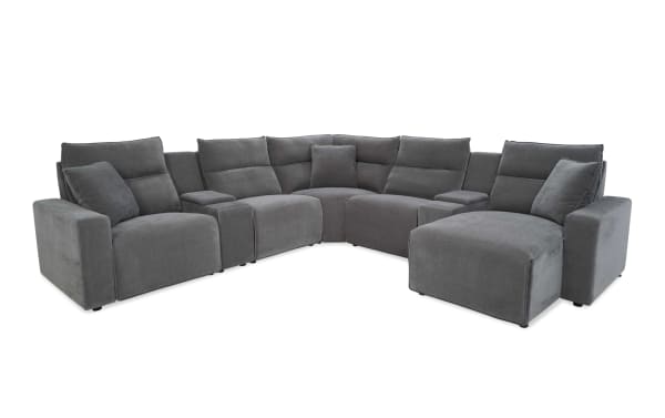 Modern gray fabric sectional sofa with plush cushions, wide armrests, and a chaise lounge, designed for spacious living rooms.