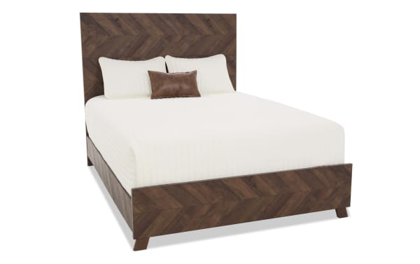 Queen-size wooden bed frame with chevron-patterned headboard and footboard in dark walnut finish, styled with white bedding and brown accent pillow.