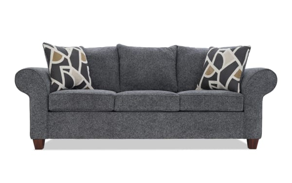 Gray fabric upholstered sofa with rolled arms, three seat cushions, three back cushions, and two decorative geometric pattern throw pillows.