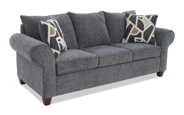 Gray fabric upholstered three-seat sofa with rolled arms, wooden legs, and two decorative geometric-patterned throw pillows.