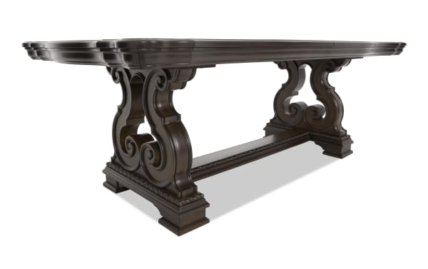 Dark brown wooden dining table with ornate carved scrollwork legs and a rectangular top, showcasing classic craftsmanship and elegant design.