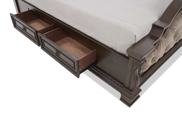 Dark wood bed frame with ornate carved details and two open storage drawers at the foot, showcasing spacious under-bed storage.