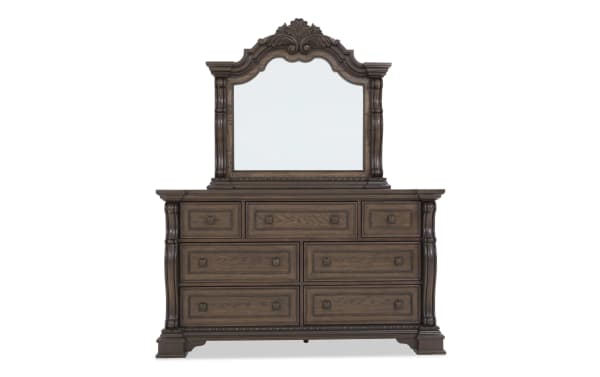 Traditional dark brown wooden dresser with ornate carved details, six large drawers, three smaller drawers, and a matching decorative mirror.