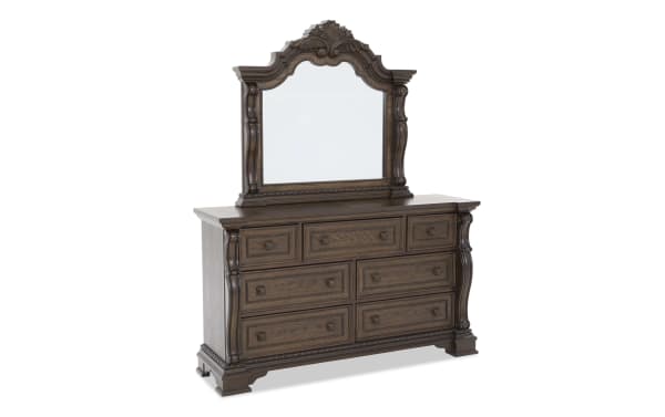 Dark brown wooden dresser with ornate carved details, six large drawers, three smaller drawers, and a matching decorative framed mirror.
