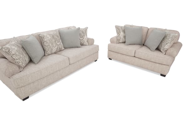 Beige fabric living room sofa set with rolled arms, dark wooden legs, and decorative patterned and solid throw pillows, ideal for modern home decor.