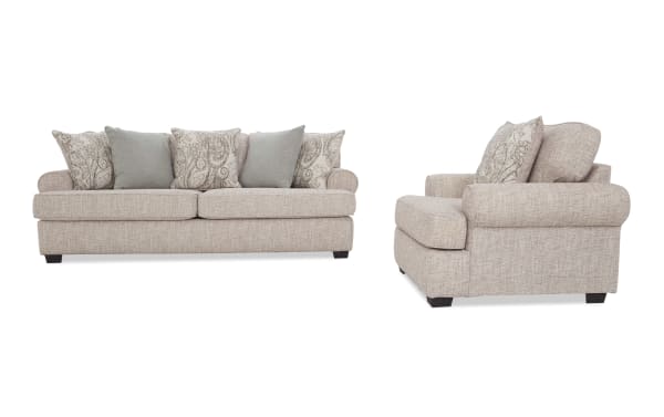 Beige fabric sofa set with rolled arms and dark wooden legs, featuring patterned and solid throw pillows, showcasing a classic, comfortable living room style.