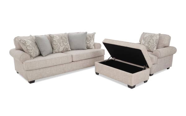 Beige fabric living room set with a three-seater sofa, matching armchair, and storage ottoman with lift-up lid, featuring patterned and solid throw pillows.