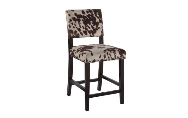 Corey Udder Madness multi upholstered counter height stool with brown and white cow print polyester fabric, rubberwood legs, and antique bronze nailhead trim.