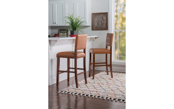 Marie Brown faux leather upholstered bar height stools in camel brown with nailhead trim, rubberwood frame, and contemporary style for kitchen counters.