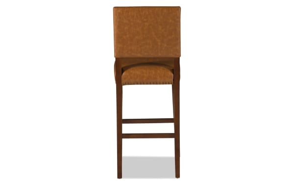 Contemporary Marie Brown faux leather upholstered bar height stool with camel polyurethane seat, nailhead trim, and solid rubberwood frame.