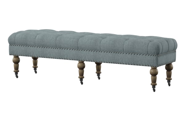 Delfina Washed Blue 62'' Bench with traditional button tufting, brushed silver nailhead trim, and turned rubberwood legs on casters. Upholstered in washed blue linen fabric with plywood and MDF frame.