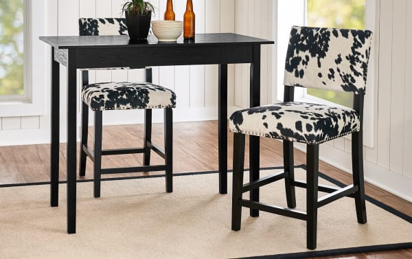 Corey Black & White Upholstered Counter Height Stool with cowprint polyester fabric, matte black rubberwood frame, and silver nailhead trim, traditional style