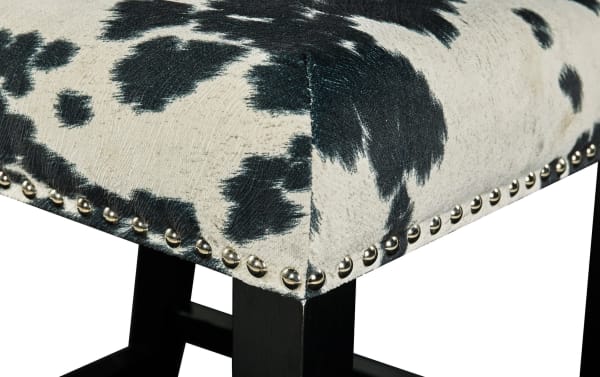 Corey Black & White Upholstered Bar Height Stool with cowprint polyester fabric, matte black rubberwood legs, and silver nailhead trim, traditional style.