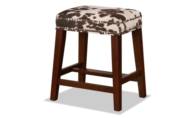 Kristen Cow Print Walnut Backless Upholstered Counter Height Stool with brown rubberwood legs, polyester fabric seat in bold cow print, and silver nailhead trim.