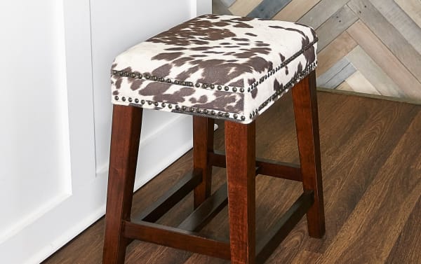Kristen Cow Print Walnut Backless Upholstered Counter Height Stool with brown cowprint polyester fabric, walnut rubberwood frame, and silver nailhead trim.