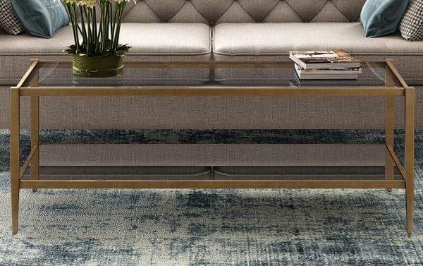 Patricia Brass Coffee Table with glam style, featuring a gold steel frame, tempered glass top, and mirrored lower shelf for elegant living room storage.