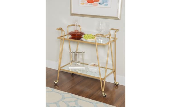 Beau Gold Bar Cart with mid-century modern style, gold steel frame, mirrored two-tier shelves, and caster wheels for easy mobility.