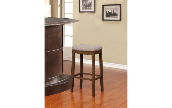 Ryann Gray Upholstered Backless Bar Height Stool with gray linen fabric seat, brushed silver nailhead trim, and rustic rubberwood frame.