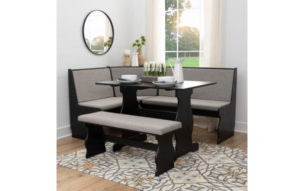 Black wood corner dining nook set with gray upholstered cushions, rectangular table, and matching bench on patterned rug in bright room.