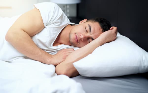 Man lying on a white MyBob's King Cooling Memory Fiber Pillow with a breathable cotton fabric cover, traditional style.
