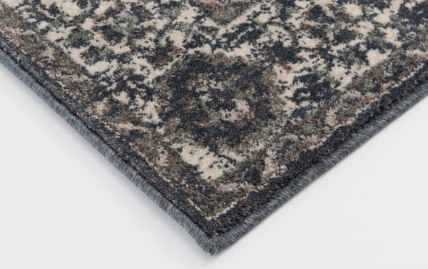 Corner close-up of the Anny 5' x 7' Blue Traditional Rug showing blue and ivory oriental pattern in stain-resistant polypropylene with transitional style.