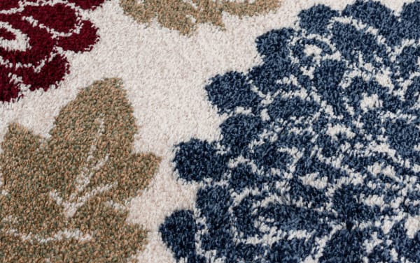 Transitional Carn 5' x 7' Ivory Floral Rug with multicolored polypropylene fibers, featuring a cozy texture and vibrant blue, red, orange, and purple floral patterns.