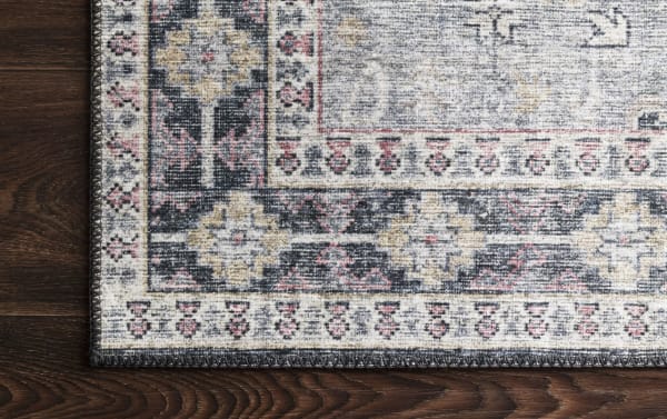 Traditional Lyudmila 8' x 10' Charcoal Oriental Rug with multicolored old-world design in polyester fabric, featuring charcoal, gray, blush, ivory, and gold tones on dark wood floor.