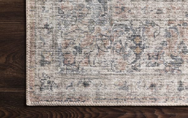 Corner detail of the Candis 8' x 10' Blush Oriental Rug showcasing its traditional multicolored blush, gray, ivory, and charcoal pattern with durable polyester fabric and stitched edges.