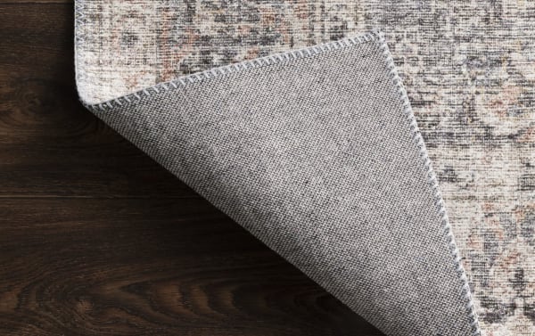 Gray oriental rug corner flipped to show woven polyester backing, featuring traditional multicolored blush, ivory, and charcoal design in 8' x 10' size.