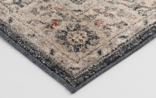 Corner detail of the Cami 3' x 5' Black Oriental Rug showing a soft polypropylene weave in black, gray, cream, and yellow with a transitional medallion pattern and durable machine-made construction.