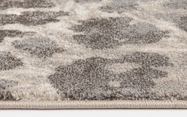 Close-up of Sharma 8' x 10' Gray Animal Print Rug edge, showing soft, durable polypropylene fibers in gray, cream, and brown with a transitional style pattern.