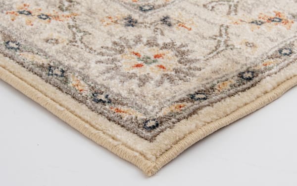 Corner close-up of the Sandra 2' x 3' Beige Oriental Rug showing its cream, beige, brown, gray, orange, and blue floral pattern with a classic border, made of durable, stain-resistant polypropylene yarn in a transitional style.