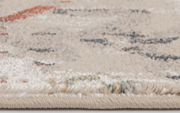 Close-up of the Solis 3' x 5' beige Ikat rug edge, showing soft polypropylene fibers in cream with subtle red, blue, orange, and yellow accents in a transitional vintage design.