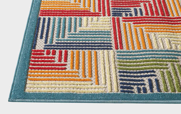Tae 5' x 7' multi geometric indoor/outdoor rug in multicolored blue, cream, orange, red, green, and purple polypropylene with abstract transitional design and textured pattern.