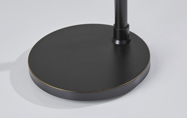 Black steel round base of the Regina 66'' Black Floor Lamp with a sturdy, transitional design supporting an arching pole.