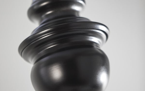 Close-up of the charcoal black turned steel base of the Alesandra 60'' Mid-Century Modern floor lamp with a smooth, rounded silhouette.