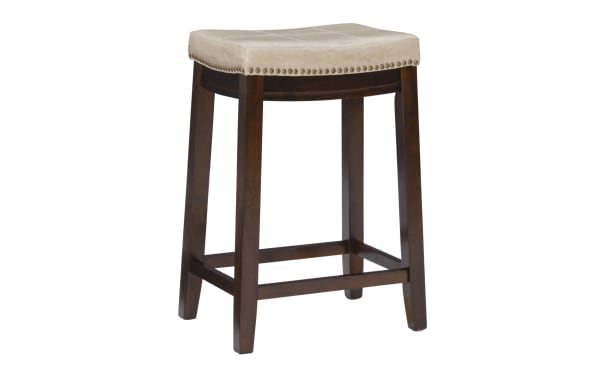 Backless Cielo Beige Faux Leather Counter Height Stool with antique brass nailhead trim, dark rubberwood legs, and transitional style upholstery.