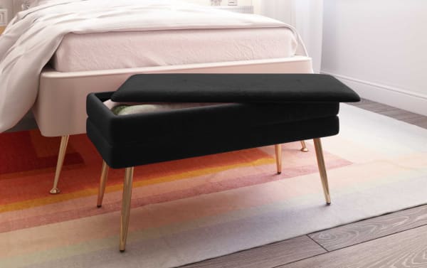 Contemporary Astrid Black Storage Bench with velvet upholstery, channel-tufted seat, and polished gold metal legs for stylish bedroom seating and storage.