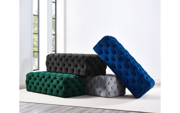 Contemporary Gemini ottomans in green, black, gray, and blue velvet with deep button tufting, plush fabric upholstery, and wooden frame.