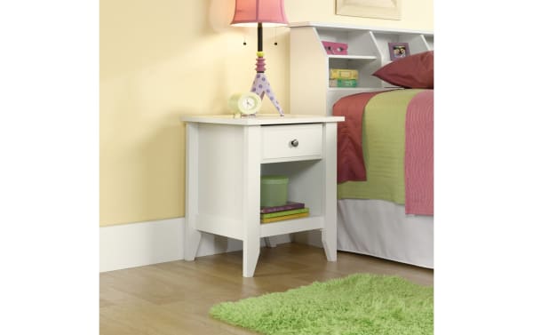Janis White Nightstand with Drawer in transitional style, made of wood with smooth metal runners, featuring a bottom storage shelf and clean white finish.