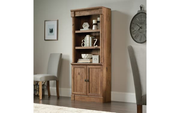 Detlof 71.9" oak transitional 2-shelf bookcase with adjustable shelves, hidden cabinet storage, and slide-on moldings in warm wood particle board.